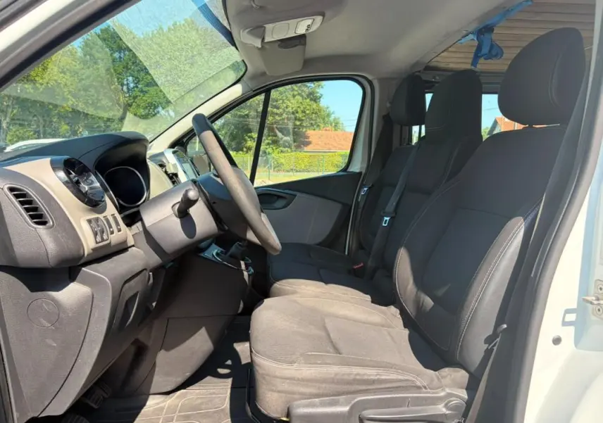 Vue intérieure côté conducteur du Renault Trafic Fourgon blanc 2018, montrant les sièges et le tableau de bord.