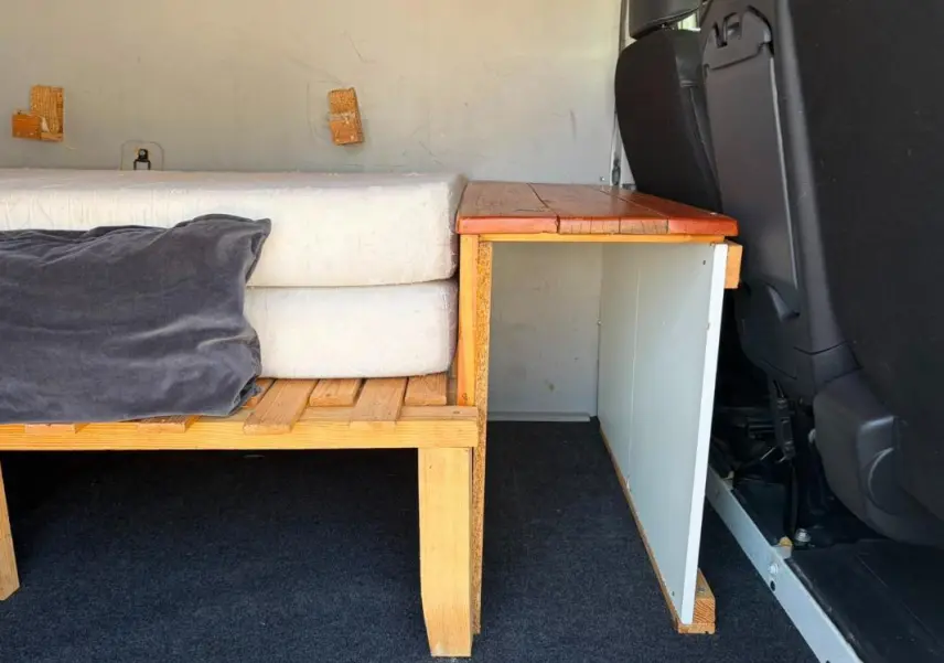 Vue intérieure latérale droite du Renault Trafic Fourgon blanc de 2018, montrant un aménagement en bois avec coussins.