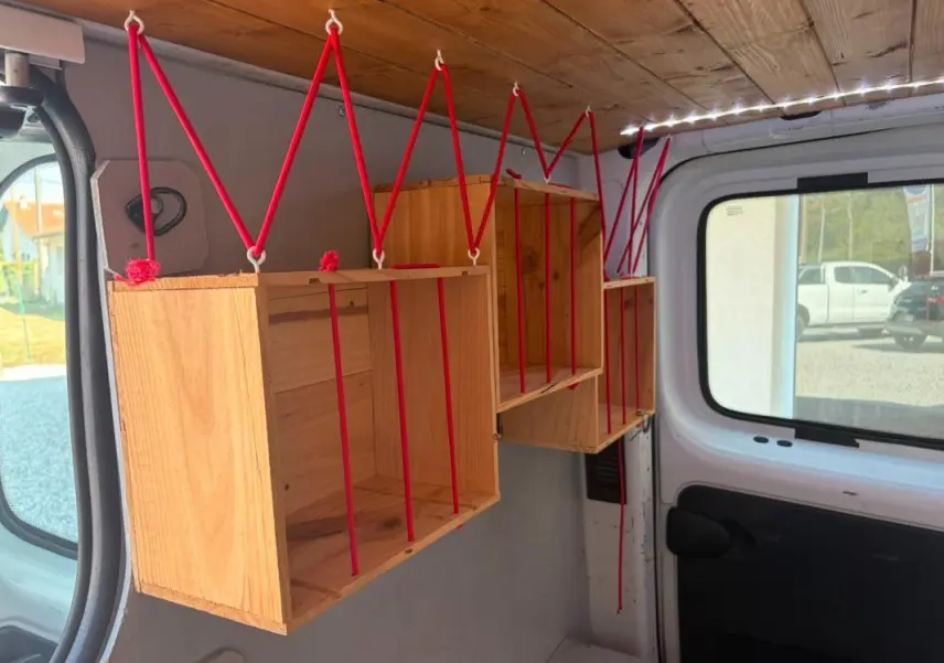Intérieur du Renault Trafic Fourgon blanc 2018, vue latérale gauche montrant des étagères en bois suspendues par des cordes rouges.