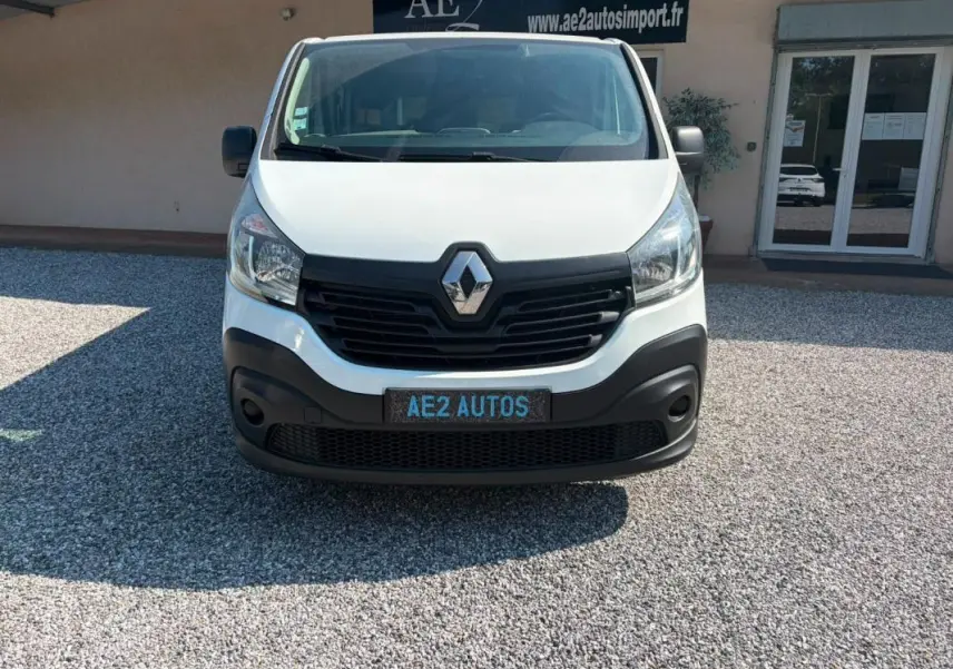 Vue frontale d’un fourgon Renault Trafic blanc de 2018 avec calandre noire et plaque AE2 AUTOS.