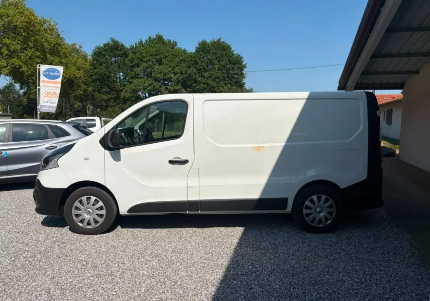 Vue de profil côté gauche du Renault Trafic Fourgon blanc 2018, avec une tache visible sur la porte latérale.