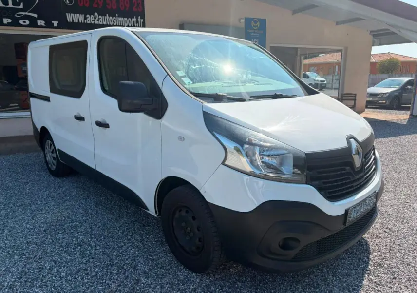Renault Trafic Fourgon blanc vu en 3/4 avant droit, avec pare-chocs noir et vitres latérales teintées.