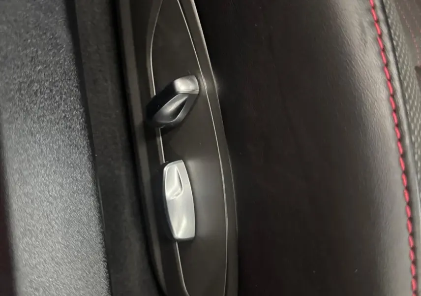 Gros plan sur les commandes de réglage électrique du siège en cuir noir avec surpiqûres rouges d'une Porsche 911 991 2 Carrera T.
