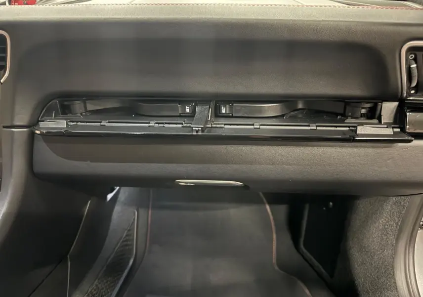 Vue intérieure du coffre à gants ouvert sur une Porsche 911 991 2 Carrera T gris GT Silver, montrant le tableau de bord noir.