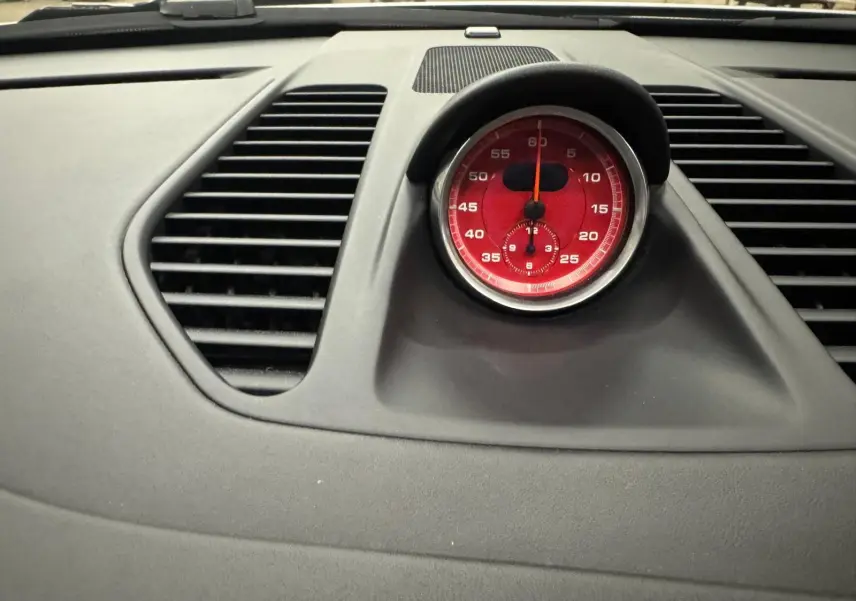 Gros plan sur le chronomètre rouge du tableau de bord gris d'une Porsche 911 991 2 Carrera T.