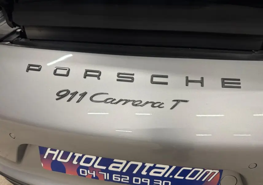 Gros plan sur l'arrière gris GT Silver d'une Porsche 911 Carrera T avec logo et badge distinctifs visibles.