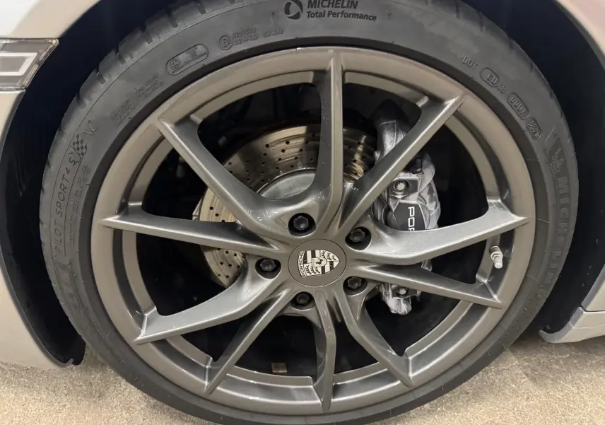Gros plan sur la jante Carrera S 20 pouces gris foncé avec étrier de frein Porsche et pneu Michelin Pilot Sport.