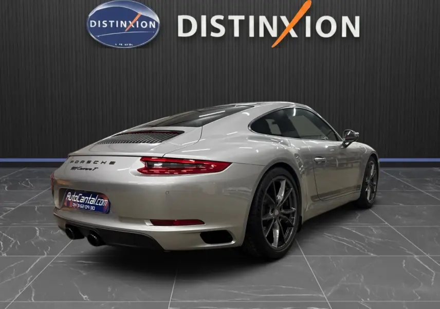 Vue 3/4 arrière droite d'une Porsche 911 Carrera T 991 gris GT Silver avec jantes Carrera S 20 pouces dans un showroom.