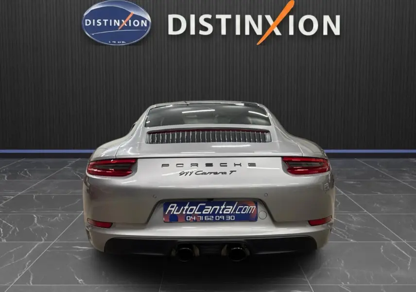 Vue arrière d'une Porsche 911 Carrera T 2018 gris GT Silver avec double sortie d'échappement et logo Porsche visible.