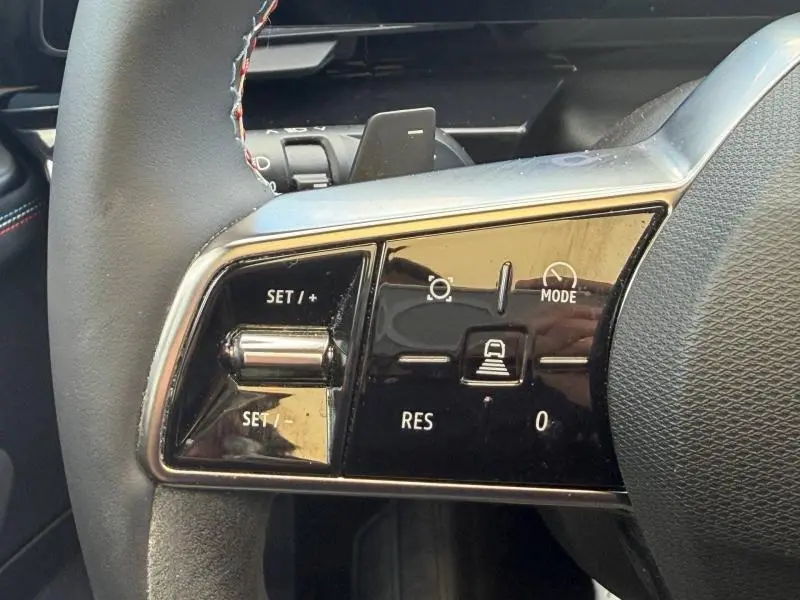 Gros plan sur les commandes au volant noir brillant de la Renault Rafale 1.2 E-Tech full hybrid 2025 côté gauche.