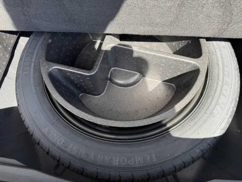 Gros plan sur la roue de secours et son rangement en plastique noir à l'arrière du Renault Rafale noir étoilé.
