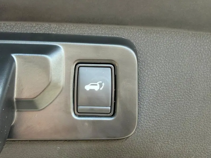 Gros plan sur le bouton d'ouverture électrique du coffre, intérieur noir texturé du Renault Rafale 2025.