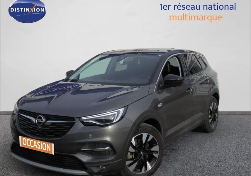 Opel Grandland X gris Moai métal en 3/4 avant droit, avec jantes alliage et calandre noire distinctive.