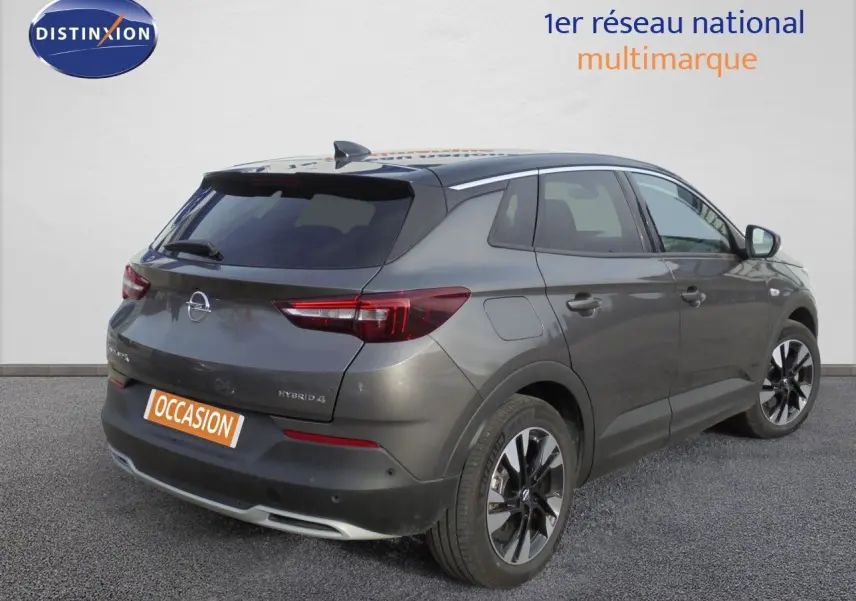 Vue 3/4 arrière droite de l'Opel Grandland X gris Moai Metal avec jantes noires et toit noir contrasté.