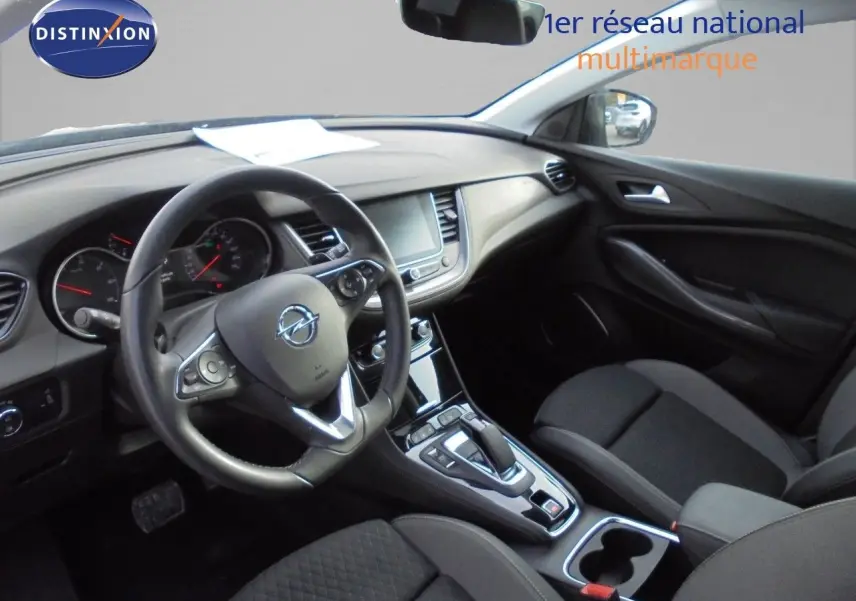 Vue intérieure côté conducteur de l’Opel Grandland X gris Moai, montrant le volant, tableau de bord et console centrale.