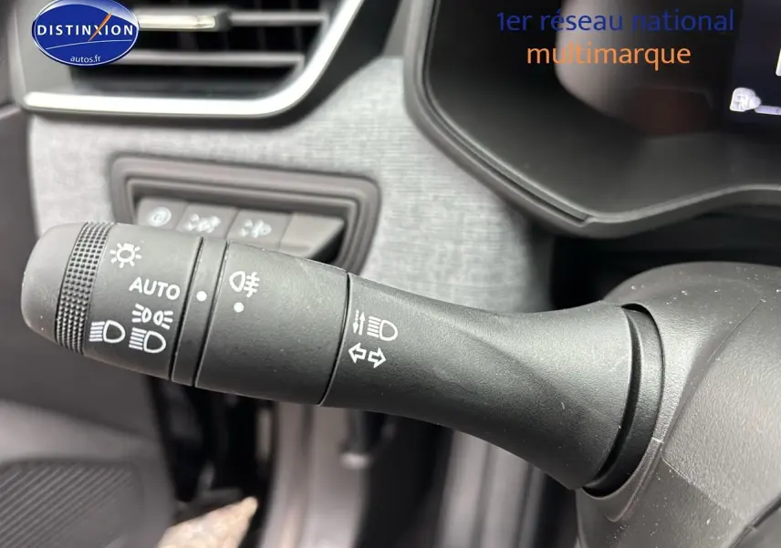 Gros plan sur la commande des phares et clignotants du tableau de bord intérieur d'une Renault Clio V noire.