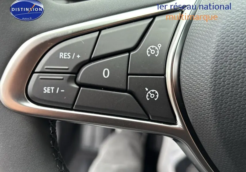 Gros plan sur les commandes du régulateur de vitesse au volant d'une Renault Clio V noire, côté gauche.