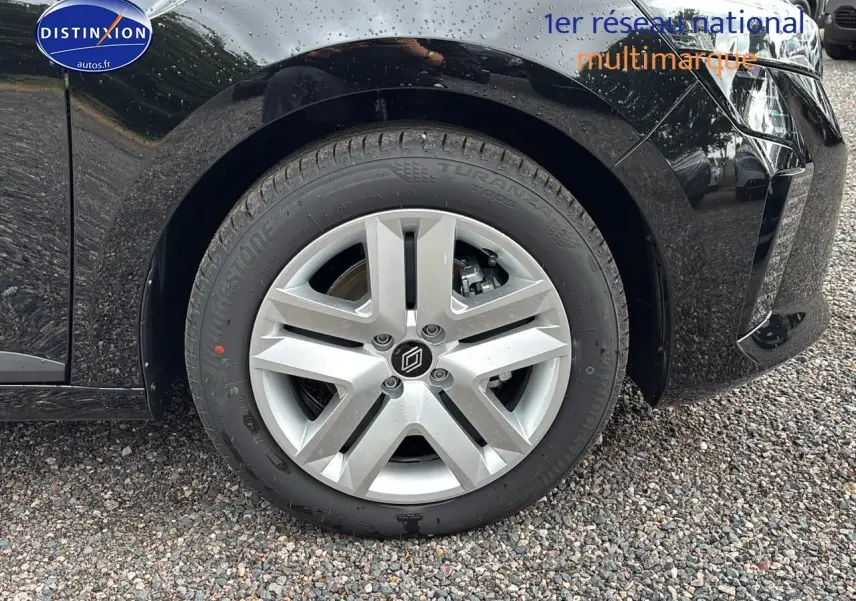 Gros plan sur la roue avant gauche de la Renault Clio V noire avec jante alliage et logo central distinctif.