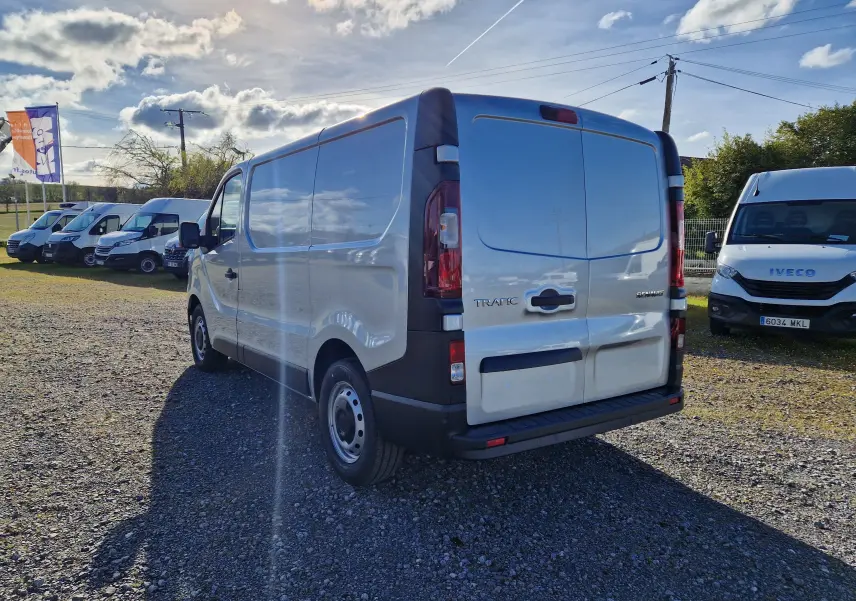 Vue 3/4 arrière droite d’un Renault Trafic Fourgon gris Highland, avec portes arrière fermées et roues acier noires.