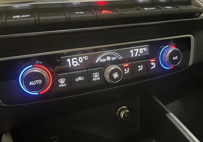 Panneau de commande de climatisation automatique de l'Audi Q2 2024 avec réglages numériques et boutons rétroéclairés.
