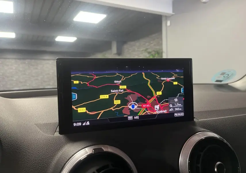 Vue intérieure du tableau de bord de l'Audi Q2 2024 avec écran de navigation affichant une carte routière.