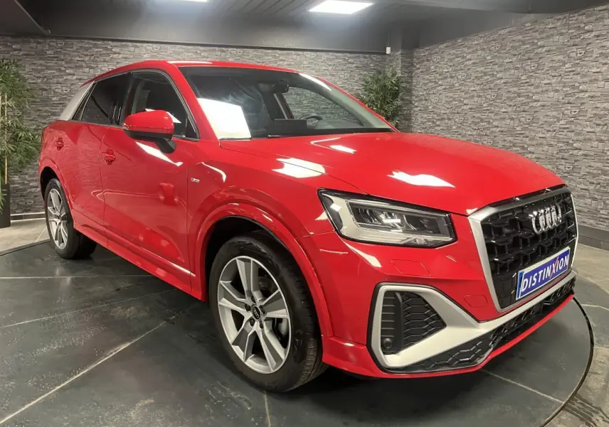 Audi Q2 S line rouge vue 3/4 avant droit, avec jantes 5 branches offroad et toit contrasté blanc.