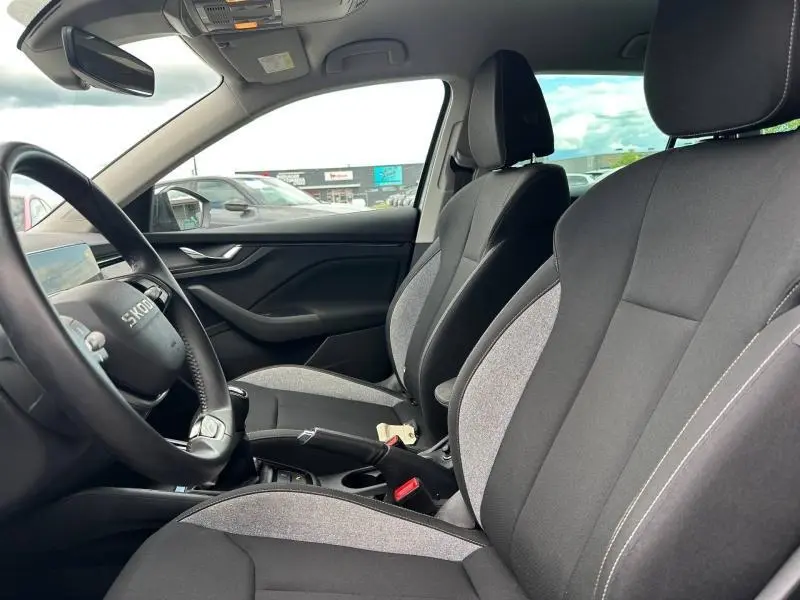 Vue intérieure côté conducteur de la Skoda Scala 2025, sièges tissu noir et gris avec volant cuir multifonction.
