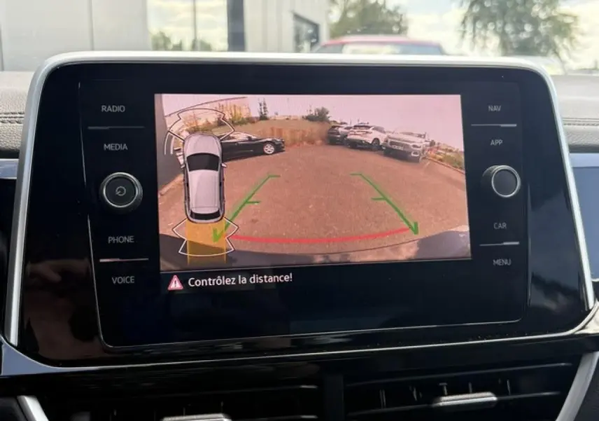 Écran tactile intérieur montrant la caméra de recul avec alertes de distance du Volkswagen T-Roc noir intense.