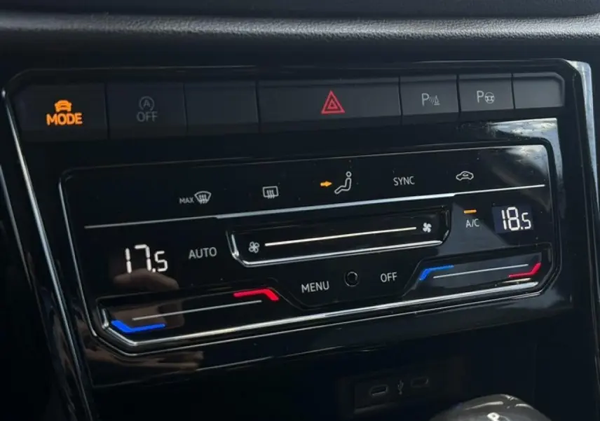 Gros plan sur la console centrale noire du Volkswagen T-Roc 2025, affichant la climatisation automatique bi-zone et commandes tactiles.
