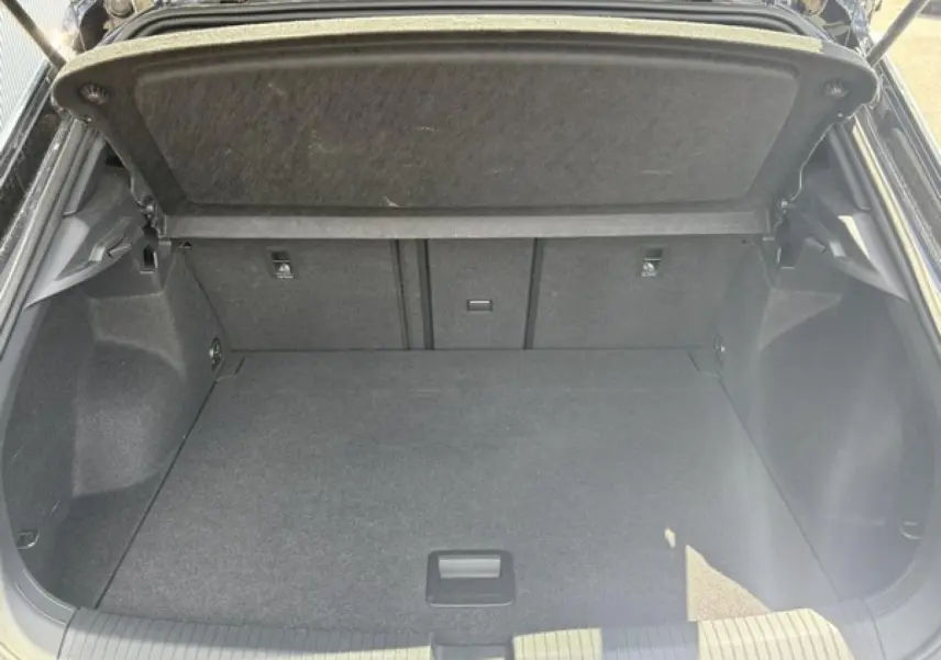Coffre ouvert vu de l'arrière d'un Volkswagen T-Roc noir intense, montrant un espace de chargement vide et propre.