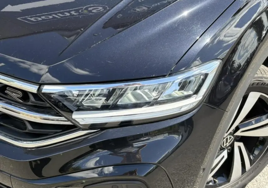 Gros plan sur l'avant droit noir intense du Volkswagen T-Roc 2025 R-Line, mettant en valeur le phare LED et la jante Nevada 18 pouces.