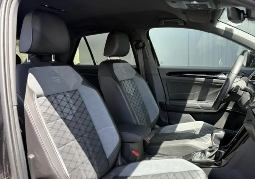 Vue intérieure côté conducteur du Volkswagen T-Roc 1.5 TSI R-Line 2025, sièges cuir et alcantara gris avec surpiqûres R-Line.