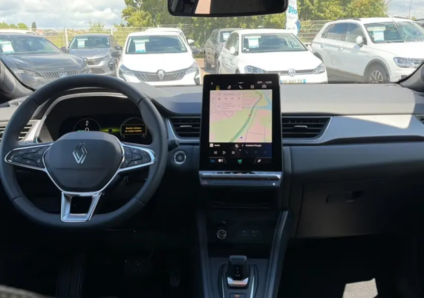 Vue intérieure avant du Renault Captur 2026, tableau de bord noir avec grand écran tactile central affichant une carte GPS.