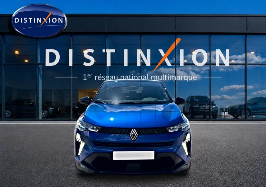 Vue avant d'un Renault Captur 2026 bleu iron avec toit noir, feux LED et calandre marquée devant un showroom Distinxion.