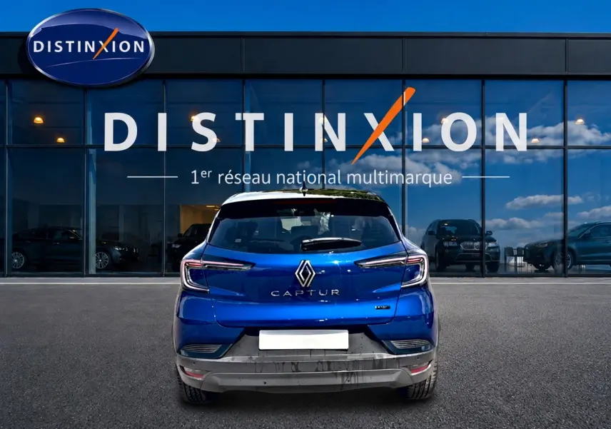 Vue arrière d'un Renault Captur bleu iron avec toit noir, garé devant une vitrine Distinxion.