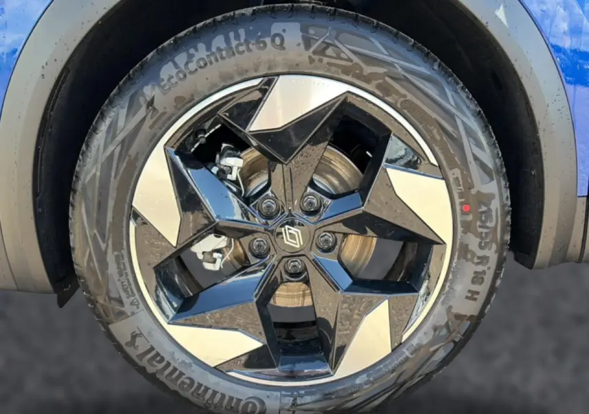 Gros plan sur la jante alu noire et argentée du côté avant droit du Renault Captur bleu iron avec toit noir.