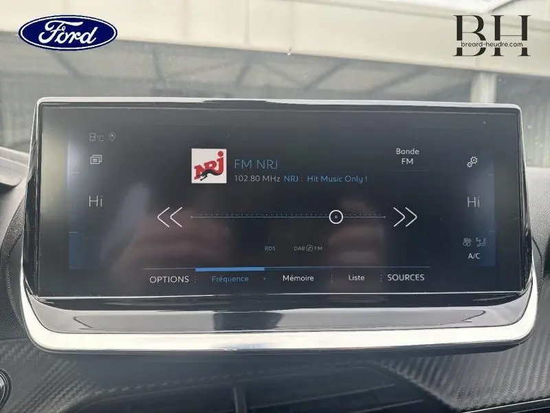 Écran tactile multimédia de la Peugeot 2008 2020, affichant la radio FM NRJ, vue intérieure centrée.