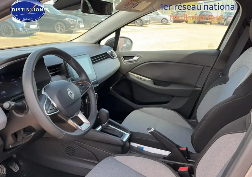 Vue intérieure côté conducteur de la Renault Clio V 1.0 TCe 90 gris métal avec volant multifonction et sièges tissu gris.