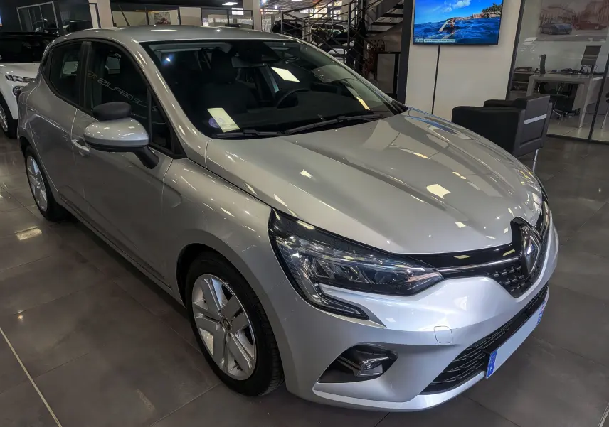 Renault Clio V gris platine vue 3/4 avant droit en intérieur, avec phares LED et jantes alliage.