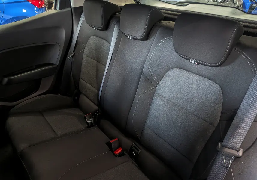 Vue intérieure des sièges arrière en tissu gris foncé de la Renault Clio V TCe 90 CH AUTO-ECOLE, avec ceintures de sécurité visibles.