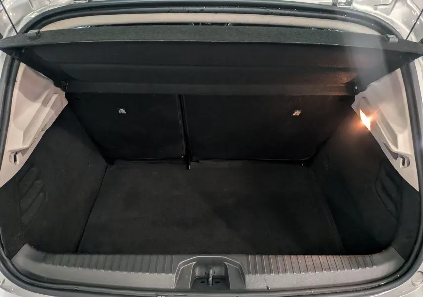 Coffre ouvert vu de l'arrière d'une Renault Clio V gris platine, intérieur noir avec éclairage latéral droit.
