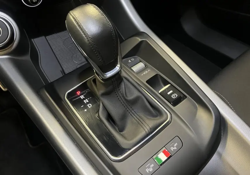 Gros plan sur la console centrale de l'Alfa Romeo Tonale 2024, levier de vitesse cuir noir et commandes de stationnement.