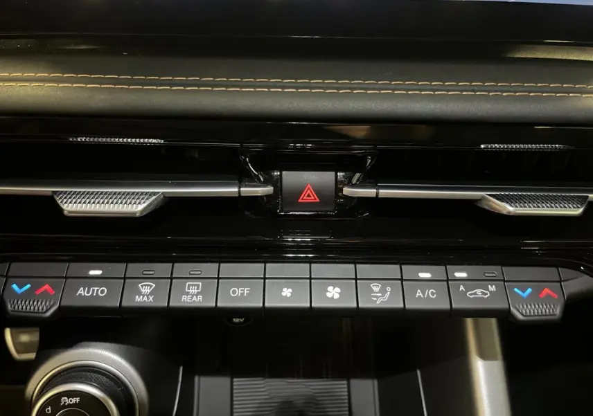 Détail du tableau de bord de l'Alfa Romeo Tonale 2024, montrant les commandes de climatisation et le bouton de signalisation.