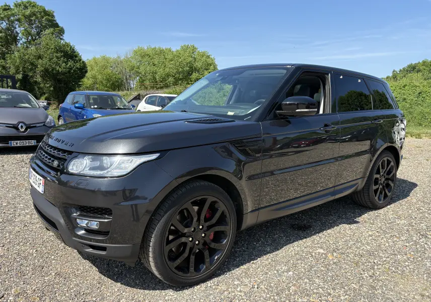 Vue 3/4 avant droite d'un Range Rover Sport Mark III gris foncé avec jantes noires et étriers rouges, stationné en extérieur.