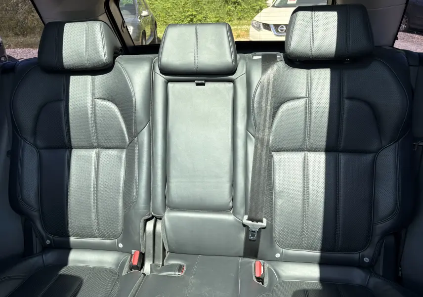Vue intérieure montrant les sièges arrière en cuir noir du Range Rover Sport Mark III, avec appuie-têtes et ceinture de sécurité visible.