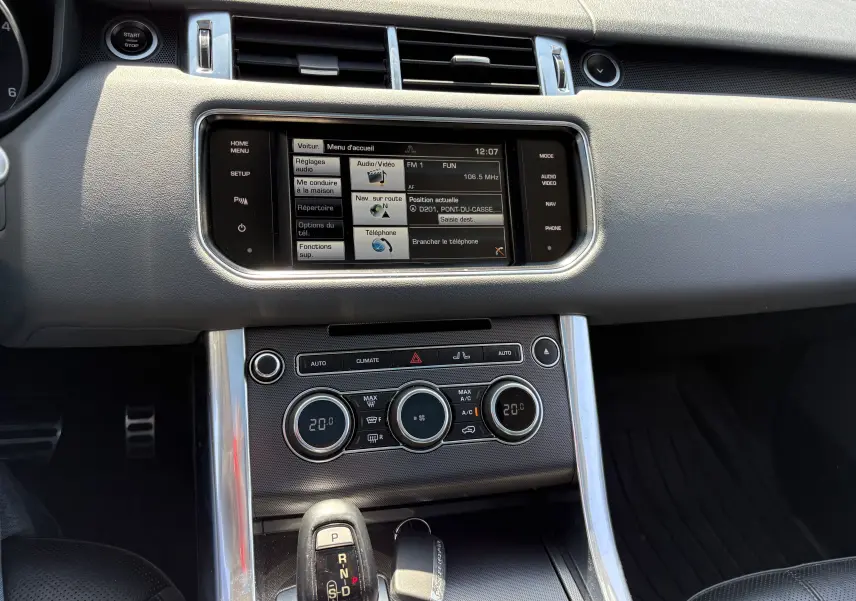 Vue rapprochée de la console centrale intérieure du Range Rover Sport 2015, avec écran tactile et commandes climatisation.