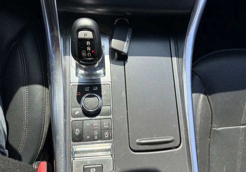 Vue plongeante sur la console centrale noire du Range Rover Sport 2015 avec levier de vitesses et clé posée.
