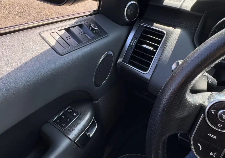 Vue intérieure côté gauche du Range Rover Sport 2015, montrant la porte avec commandes des vitres et partie du volant en cuir noir.