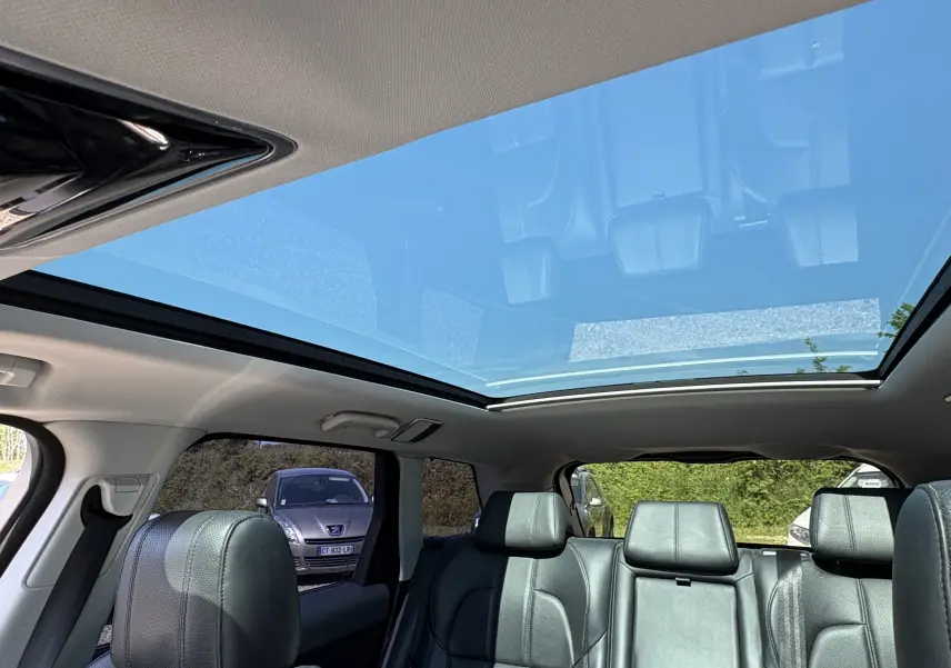 Intérieur du Range Rover Sport 2015 vu côté arrière, montrant le toit panoramique et les sièges en cuir noirs.