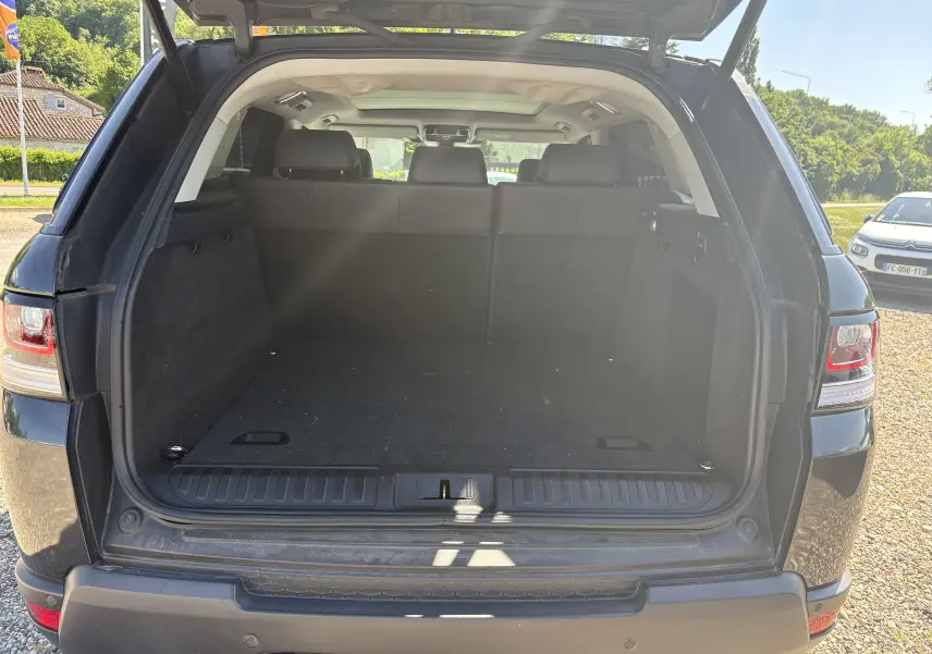 Vue arrière ouverte du coffre spacieux d'un Range Rover Sport noir 2015, avec banquette arrière et hayon relevé.